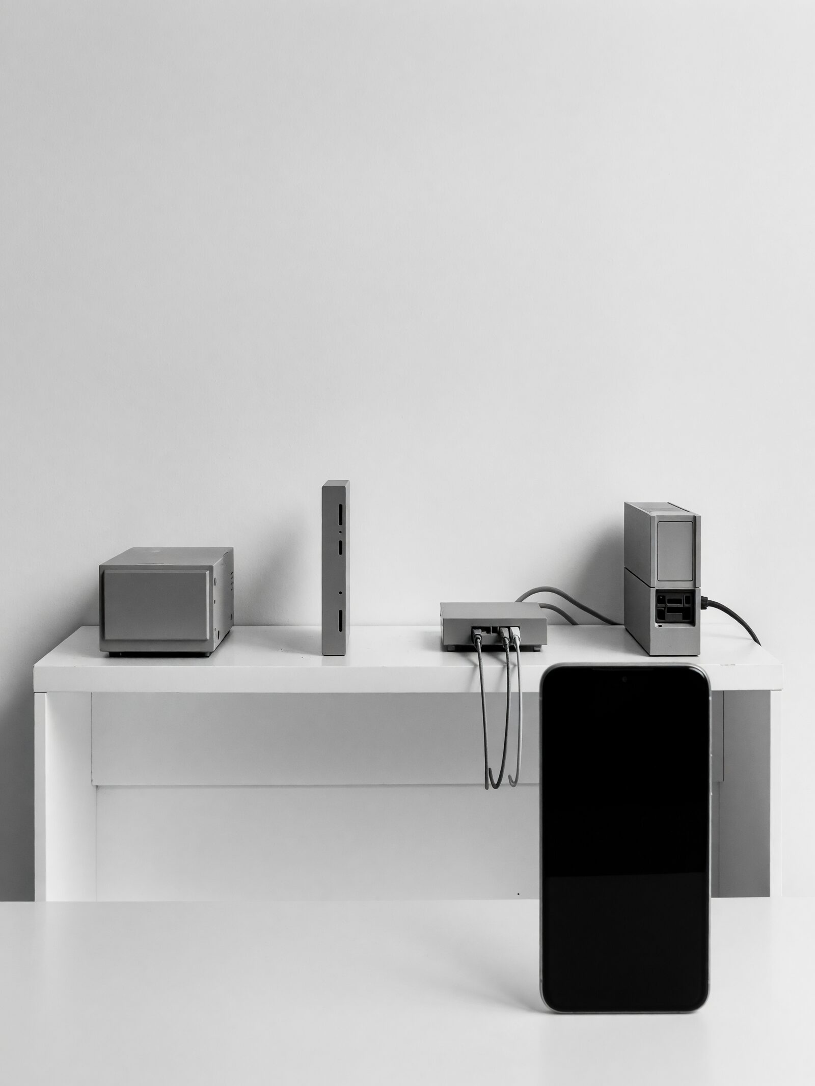 Illustration: a shelf holding a small server, an upright backup drive and a router, with an upright phone on the desk in front.